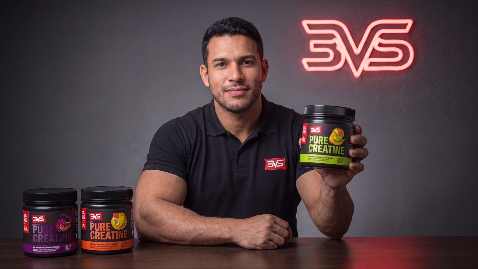 Apresentador segurando o pote de Creatina Pure sabor Cítrus, com os sabores Açaí com Uva e Frutas Tropicais sobre a mesa