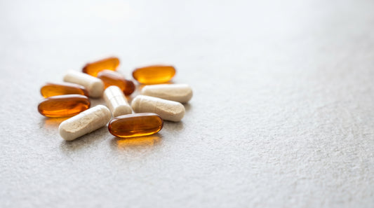 Cápsulas âmbar e creme de L-carnitina sobre pedra cinza clara — guia 3VS Nutrition